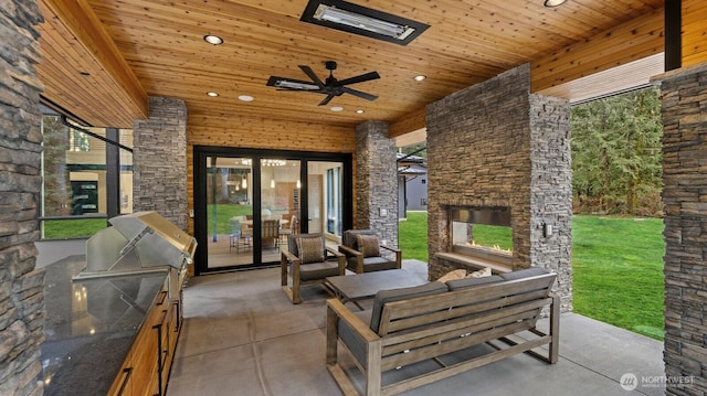 view of patio / terrace featuring an outdoor living space with a fireplace, ceiling fan, area for grilling, and exterior kitchen