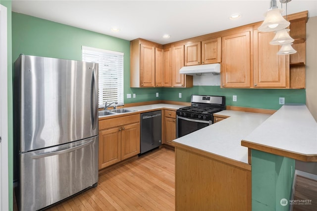 kitchen featuring sink, stainless steel appliances, decorative light fixtures, kitchen peninsula, and light wood-type flooring