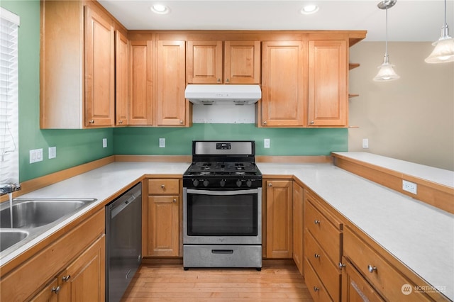 kitchen with stainless steel gas range, sink, black dishwasher, pendant lighting, and light hardwood / wood-style floors