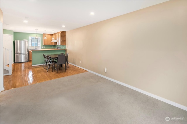 interior space with a breakfast bar, stainless steel fridge, a kitchen island, pendant lighting, and light hardwood / wood-style floors