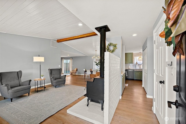 living room featuring vaulted ceiling with beams, light hardwood / wood-style floors, and a wood stove