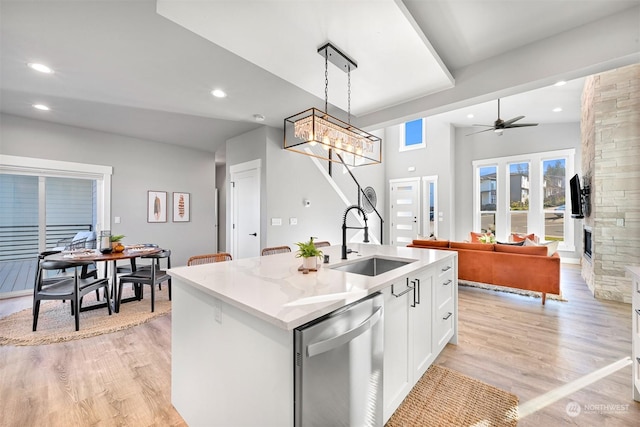 kitchen with sink, stainless steel dishwasher, an island with sink, pendant lighting, and white cabinets