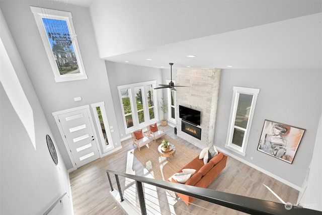 living room with ceiling fan, high vaulted ceiling, a fireplace, and light hardwood / wood-style flooring