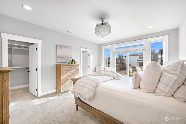 bedroom featuring light colored carpet, access to exterior, and a walk in closet