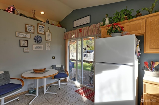 kitchen with refrigerator, vaulted ceiling, and light tile patterned floors