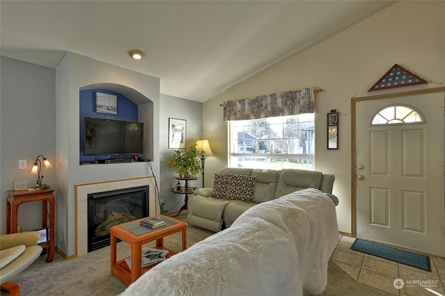 living room with a tile fireplace, vaulted ceiling, and light carpet