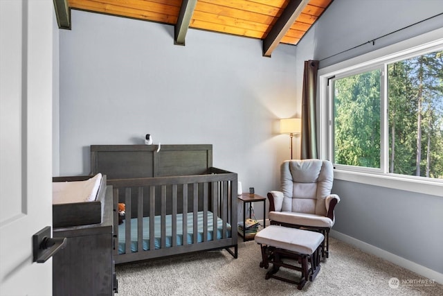 carpeted bedroom featuring vaulted ceiling with beams, a crib, wooden ceiling, and baseboards