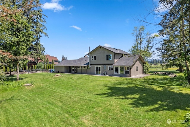 back of house with a lawn and fence