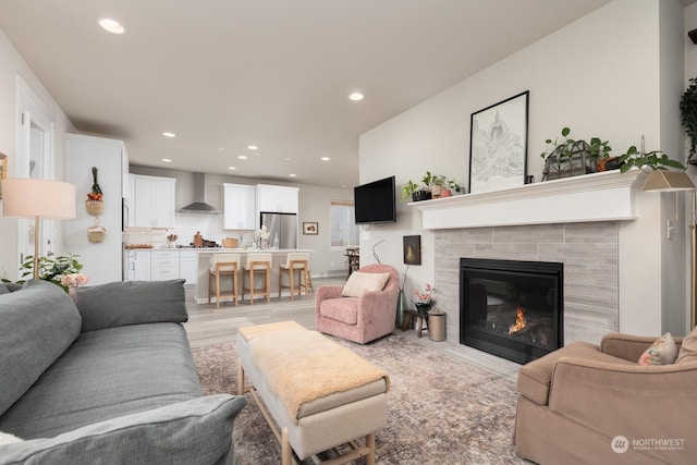 living room with a tile fireplace and light hardwood / wood-style floors