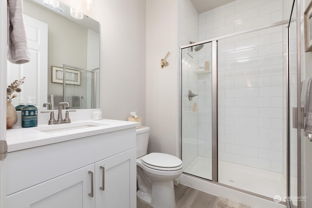 bathroom with vanity, toilet, a shower with shower door, and hardwood / wood-style floors