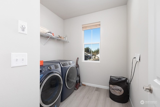 laundry room featuring washing machine and clothes dryer and light hardwood / wood-style floors