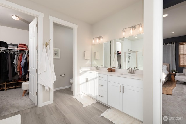 bathroom with wood-type flooring, toilet, an enclosed shower, and vanity