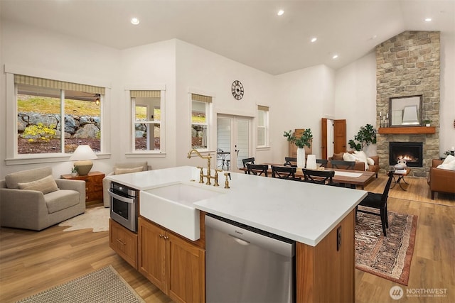 kitchen with stainless steel appliances, open floor plan, a kitchen island with sink, and a sink