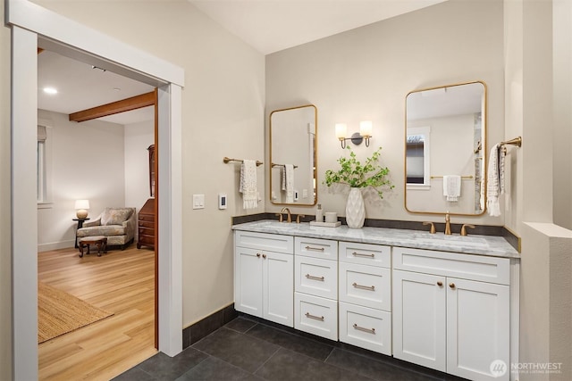 bathroom with double vanity, wood finished floors, a sink, and baseboards