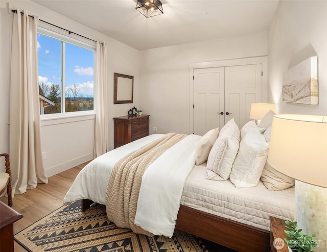 bedroom featuring a closet, light wood-style flooring, and baseboards