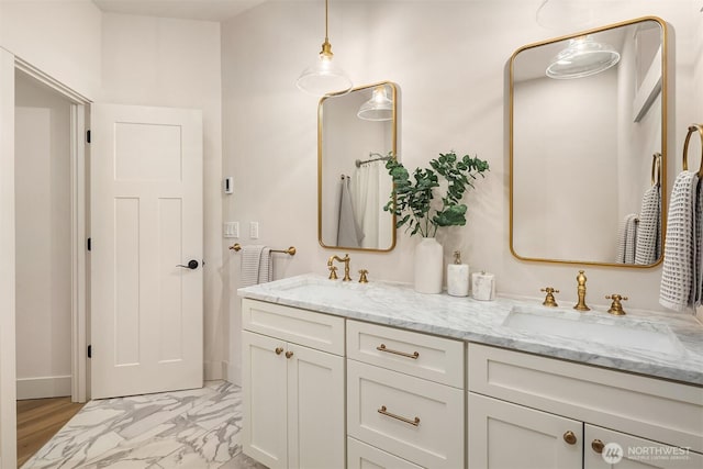 bathroom with marble finish floor, double vanity, and a sink