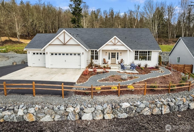 view of front facade featuring driveway, an attached garage, and fence