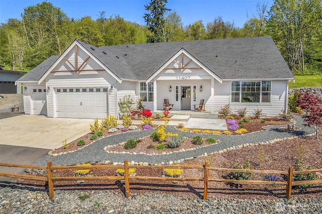 view of front facade with concrete driveway, an attached garage, a fenced front yard, and a shingled roof
