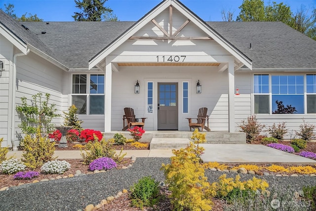 property entrance featuring a porch and roof with shingles