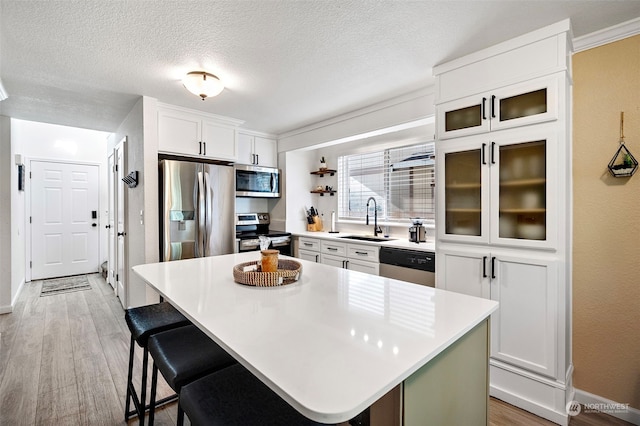 kitchen featuring white cabinetry, sink, stainless steel appliances, and a kitchen island