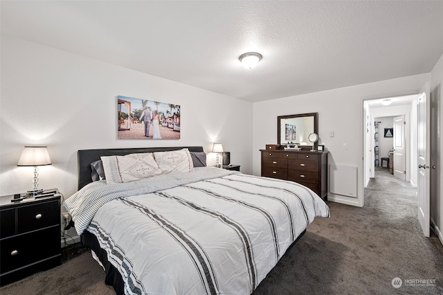 bedroom featuring dark carpet and a textured ceiling