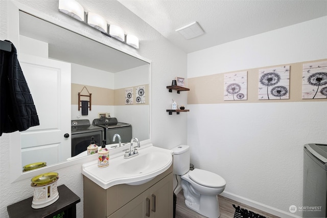 bathroom featuring separate washer and dryer, vanity, hardwood / wood-style floors, and toilet