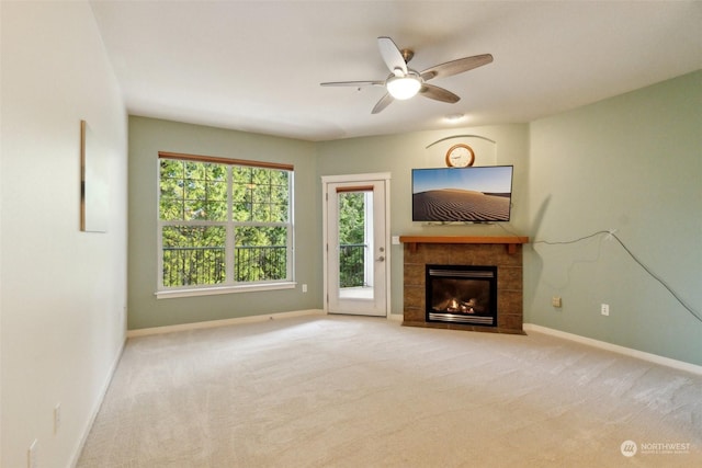 unfurnished living room featuring a tile fireplace, light colored carpet, and ceiling fan