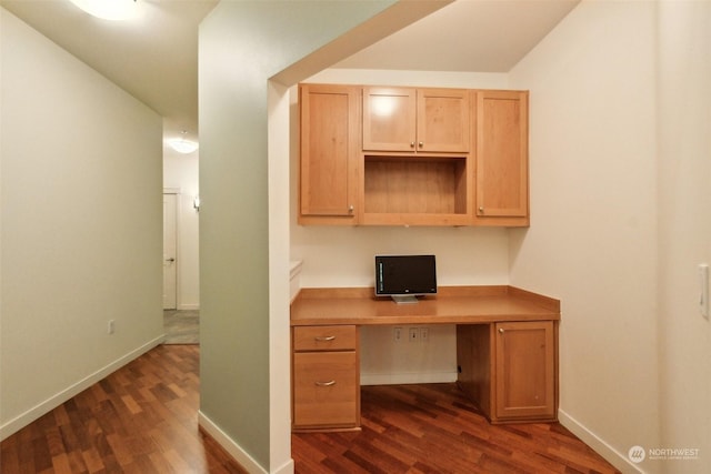 unfurnished office featuring dark hardwood / wood-style flooring and built in desk