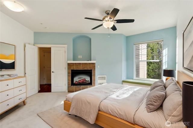 carpeted bedroom with a fireplace and ceiling fan