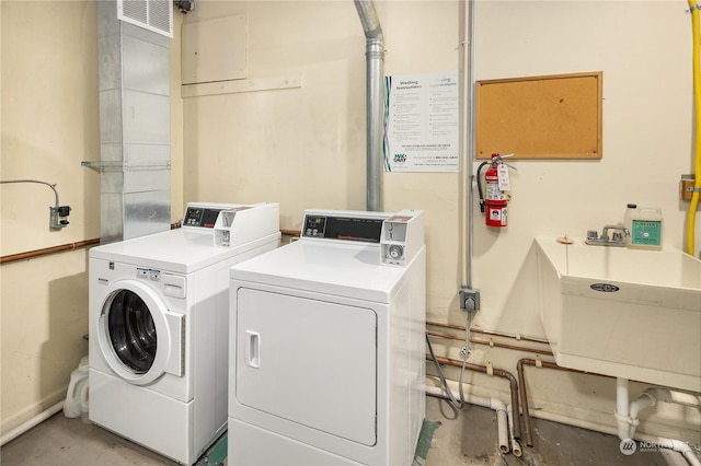 clothes washing area featuring washer and clothes dryer and sink