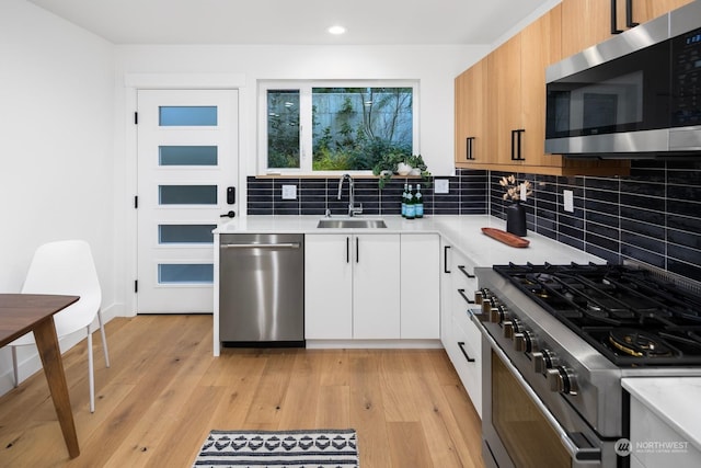 kitchen with stainless steel appliances, sink, white cabinets, and decorative backsplash