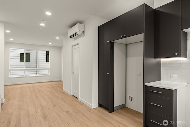 9221D 14th Ave NW, Seattle, WA 98117 - kitchen with an AC wall unit, dark cabinetry, light wood-type flooring, light countertops, and recessed lighting
