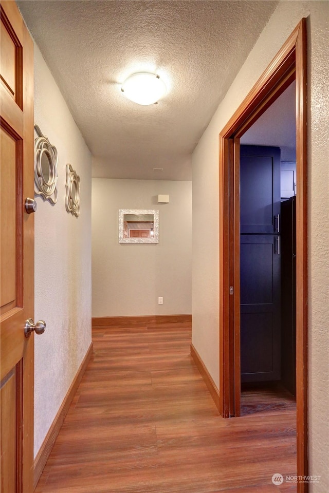 corridor featuring wood-type flooring and a textured ceiling