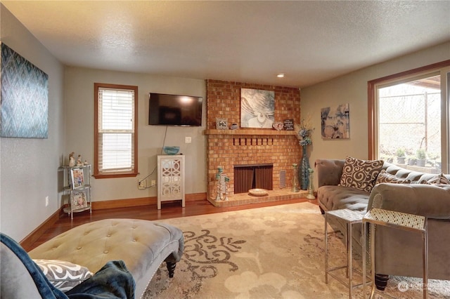 living room featuring wood-type flooring, a brick fireplace, and a textured ceiling