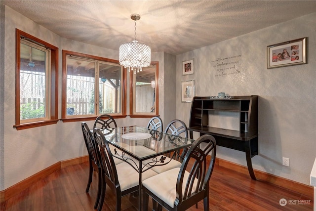 dining room with a notable chandelier, wood-type flooring, and a textured ceiling