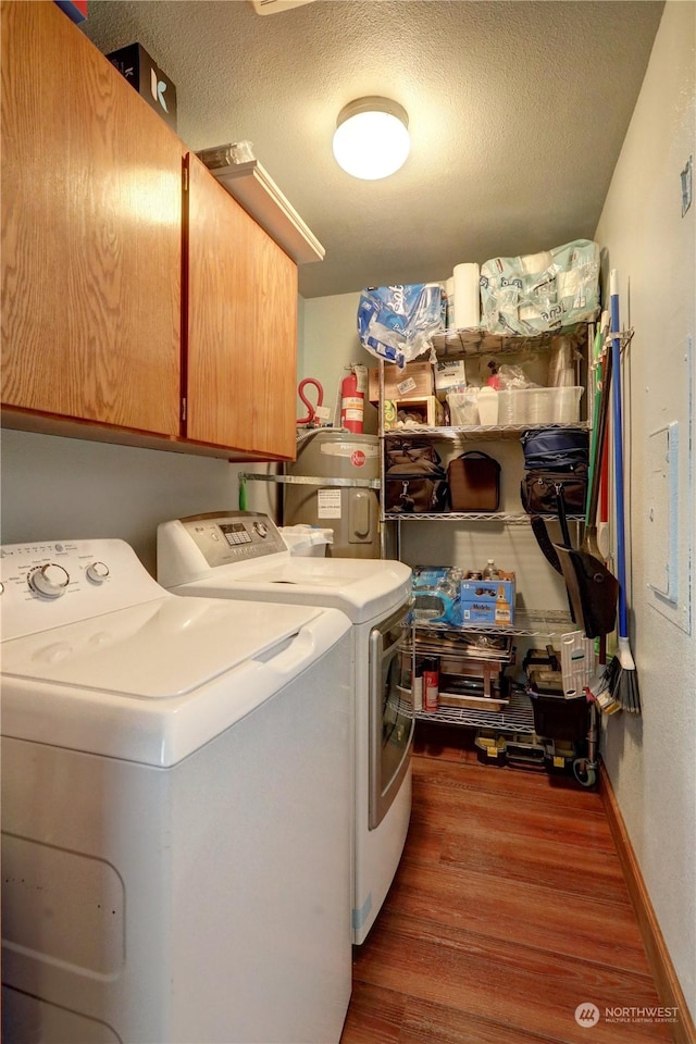 washroom featuring cabinets, washing machine and dryer, dark wood-type flooring, and a textured ceiling