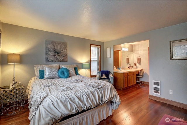 bedroom with dark wood-type flooring, ensuite bath, and heating unit