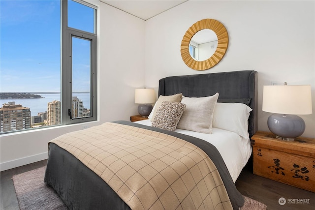 bedroom with dark wood-type flooring and a water view