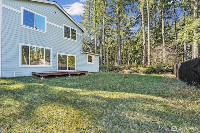 back of property featuring a yard, a deck, and fence