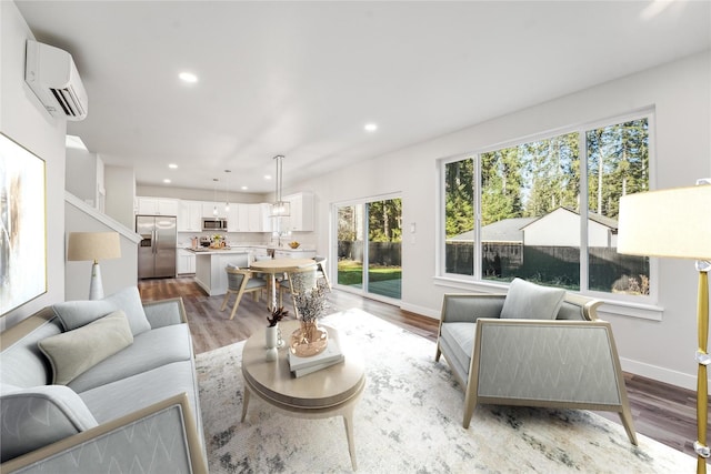 living room with recessed lighting, an AC wall unit, baseboards, and light wood finished floors