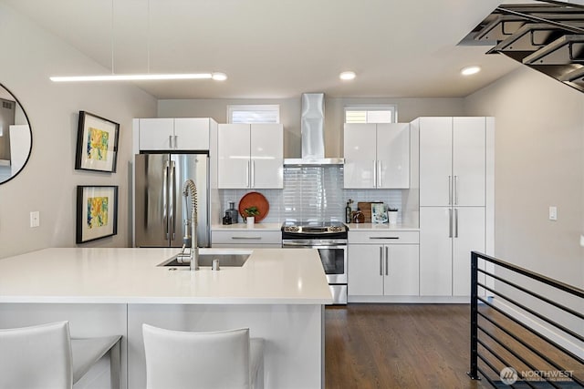 kitchen with white cabinetry, appliances with stainless steel finishes, and wall chimney range hood