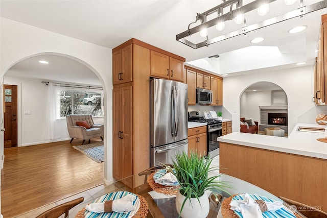 kitchen featuring stainless steel appliances, kitchen peninsula, and light hardwood / wood-style floors