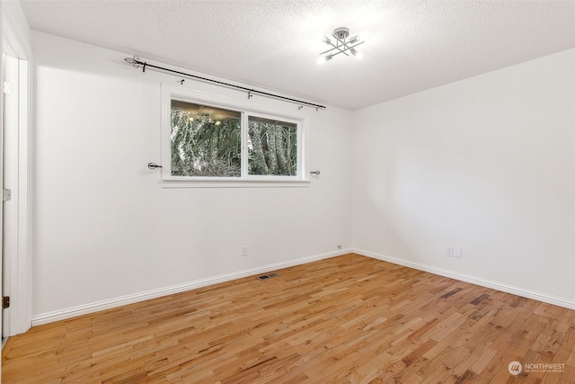 spare room featuring a textured ceiling and light wood-type flooring