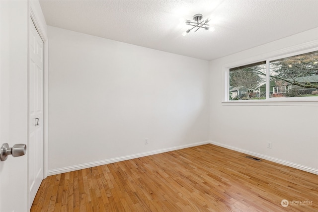 spare room featuring hardwood / wood-style floors and a textured ceiling