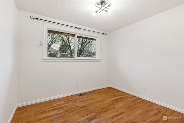 spare room featuring wood-type flooring and a textured ceiling