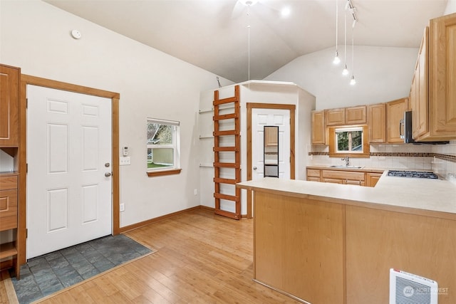 kitchen featuring tasteful backsplash, lofted ceiling, sink, kitchen peninsula, and light hardwood / wood-style flooring