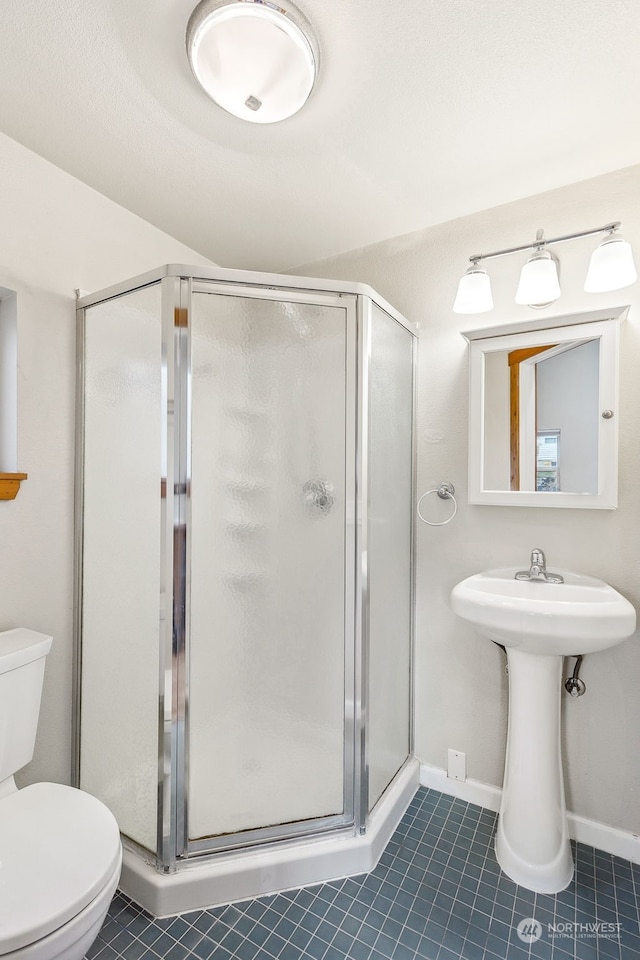 bathroom featuring tile patterned floors, toilet, and a shower with door