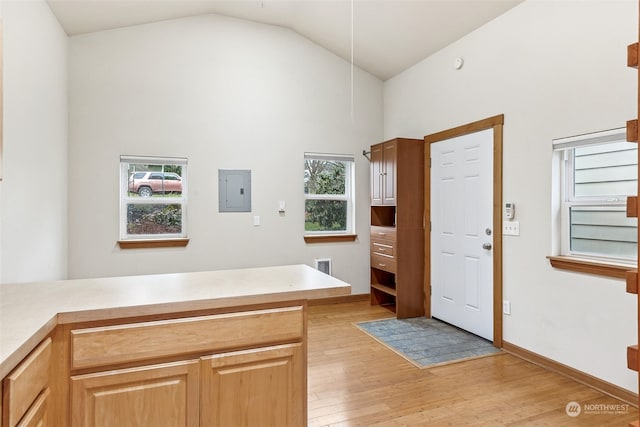 interior space featuring vaulted ceiling, electric panel, light hardwood / wood-style floors, and kitchen peninsula