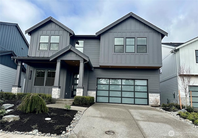 view of front facade featuring stone siding, board and batten siding, driveway, and a garage