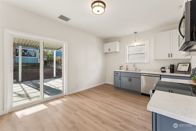 kitchen featuring appliances with stainless steel finishes, sink, white cabinets, hanging light fixtures, and a healthy amount of sunlight